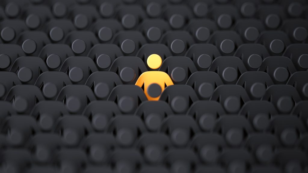 A single orange figure stands out among a crowd of black silhouettes, emphasizing individuality in a sea of uniformity.