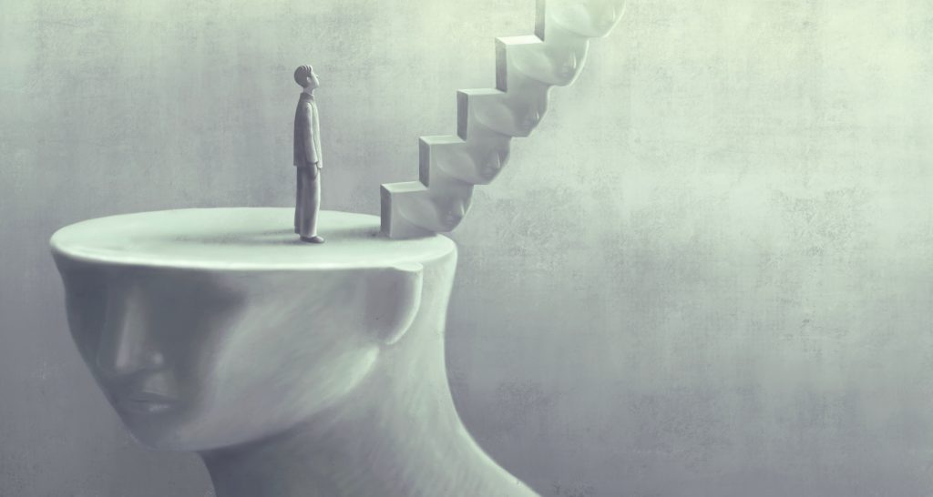 A small figure stands on a large head, gazing up at a staircase emerging from the head's top.