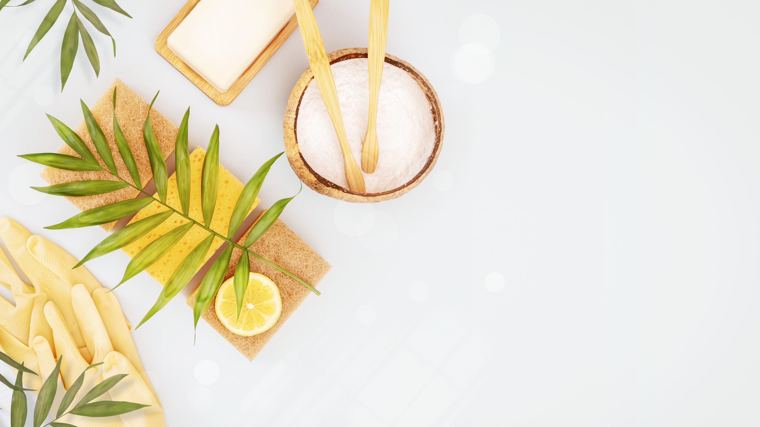 Spa essentials: a bowl of salt, lemon slices, green leaves, and exfoliating tools on a light background.