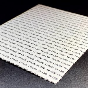 Square sheet of paper printed with repeated "LSD" text in a grid pattern, on a dark background.
