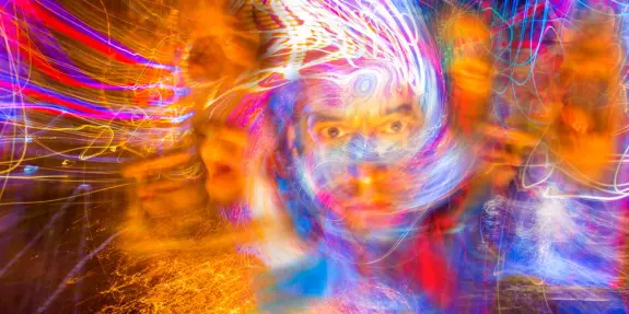 Swirling colors and lights create an abstract, dreamlike portrait with a central face surrounded by vibrant patterns.