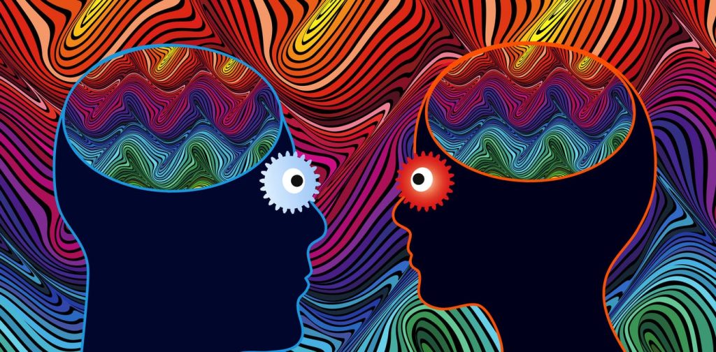 Two silhouetted heads face each other, with colorful, swirling patterns inside their brains and contrasting gears for eyes.