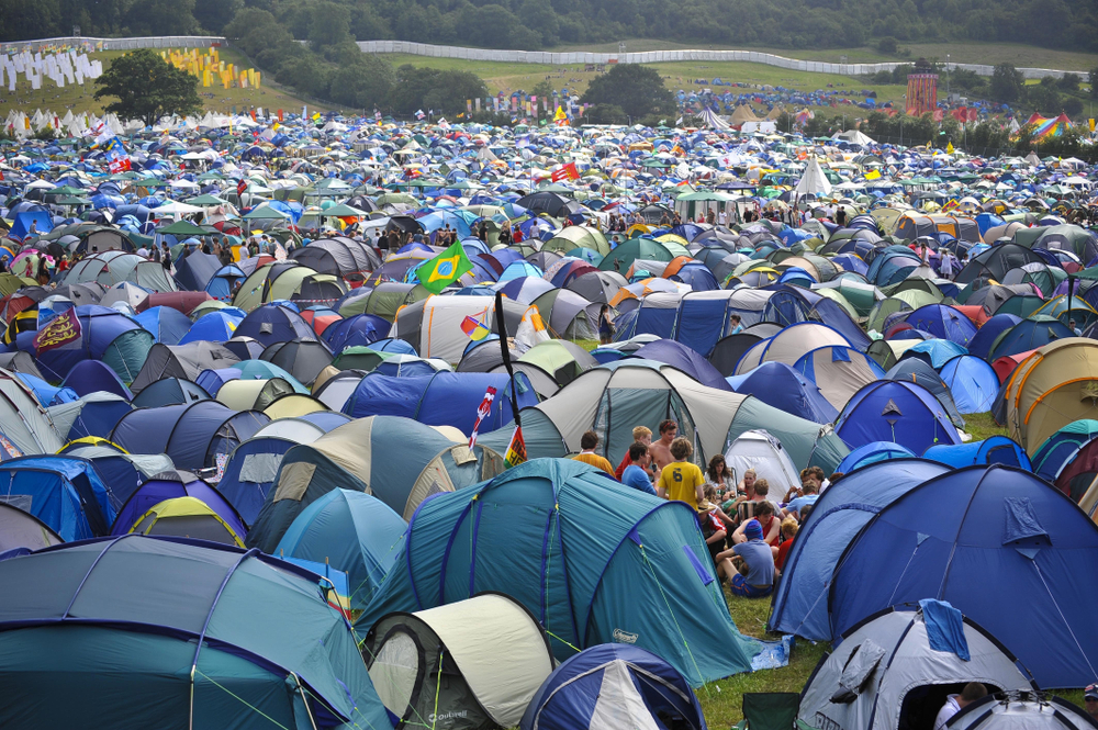 A vast field filled with colorful tents, bustling with festival-goers amidst a lively outdoor atmosphere.