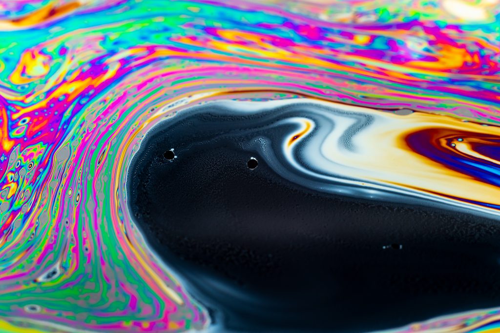 Vibrant, swirling patterns of color with black and white streaks, resembling a psychedelic abstract painting.