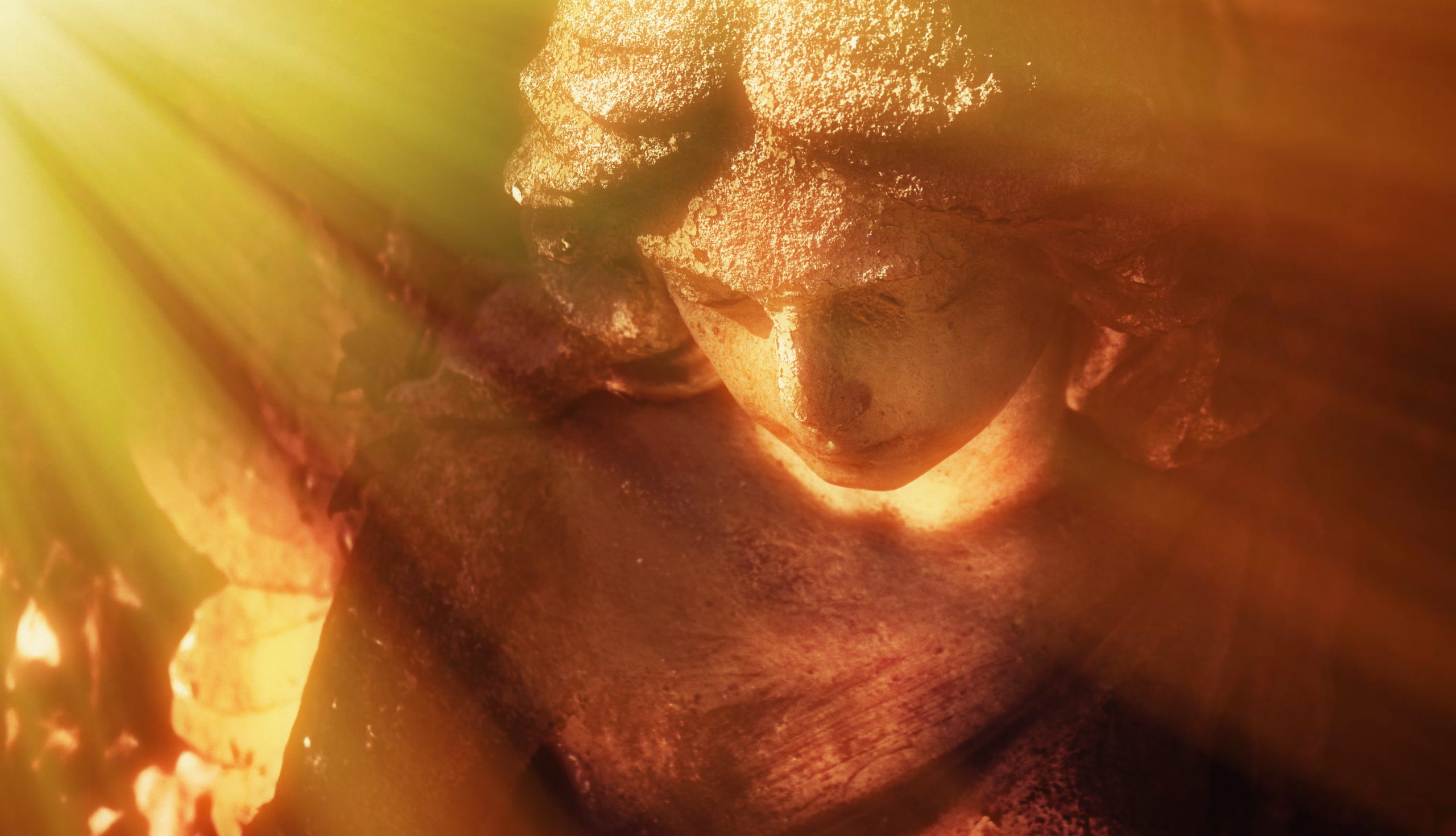 A weathered statue of a woman with flowing hair, illuminated by warm rays of sunlight, creating a serene atmosphere.