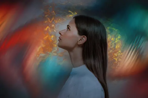 Woman with long hair gazes upward against a vibrant, swirling abstract background of colors.
