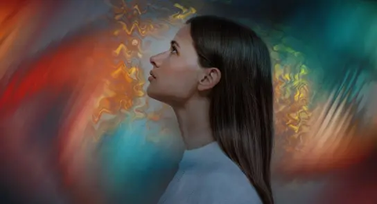 Woman with long hair gazes upward against a vibrant, swirling abstract background of colors.