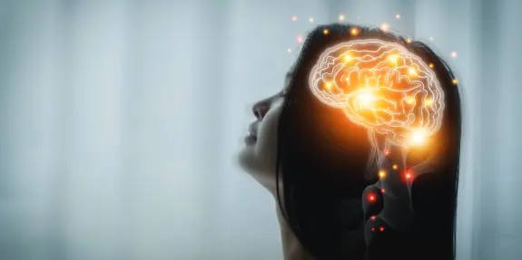 Woman's silhouette with a glowing brain illustration, symbolizing thought and creativity against a soft background.